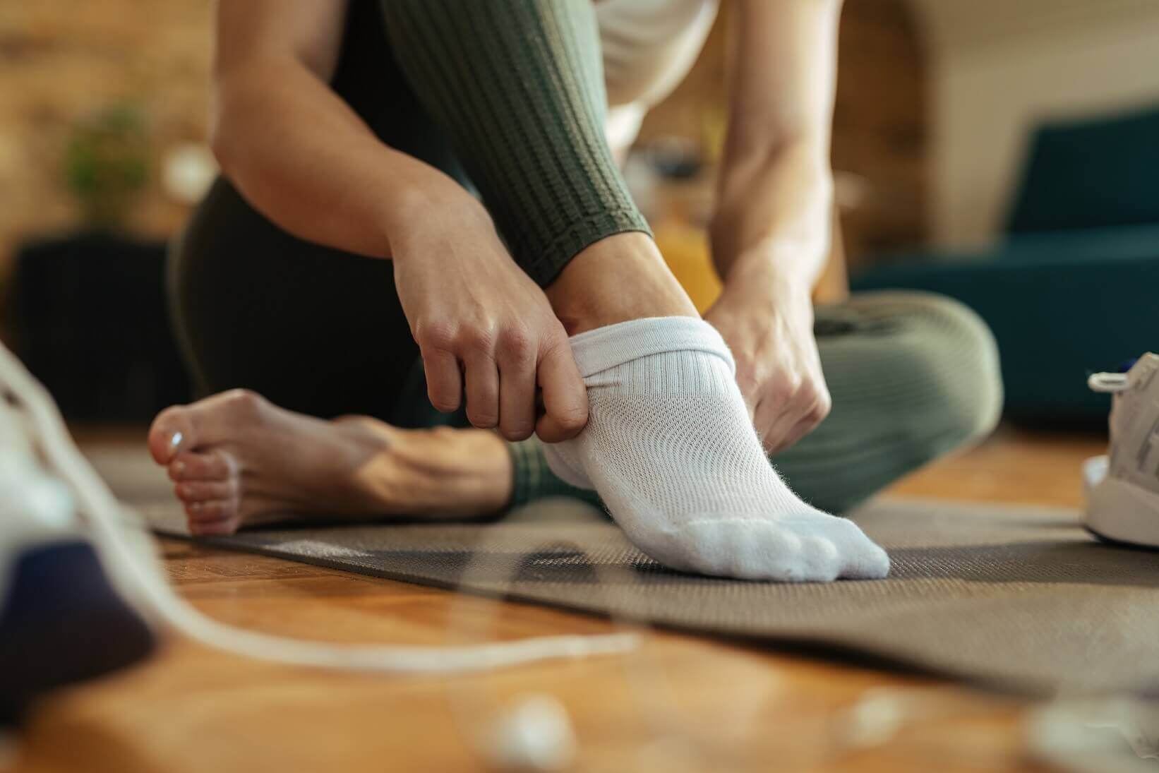 Close-up of sportswoman wearing white athletic socks pre-workout.